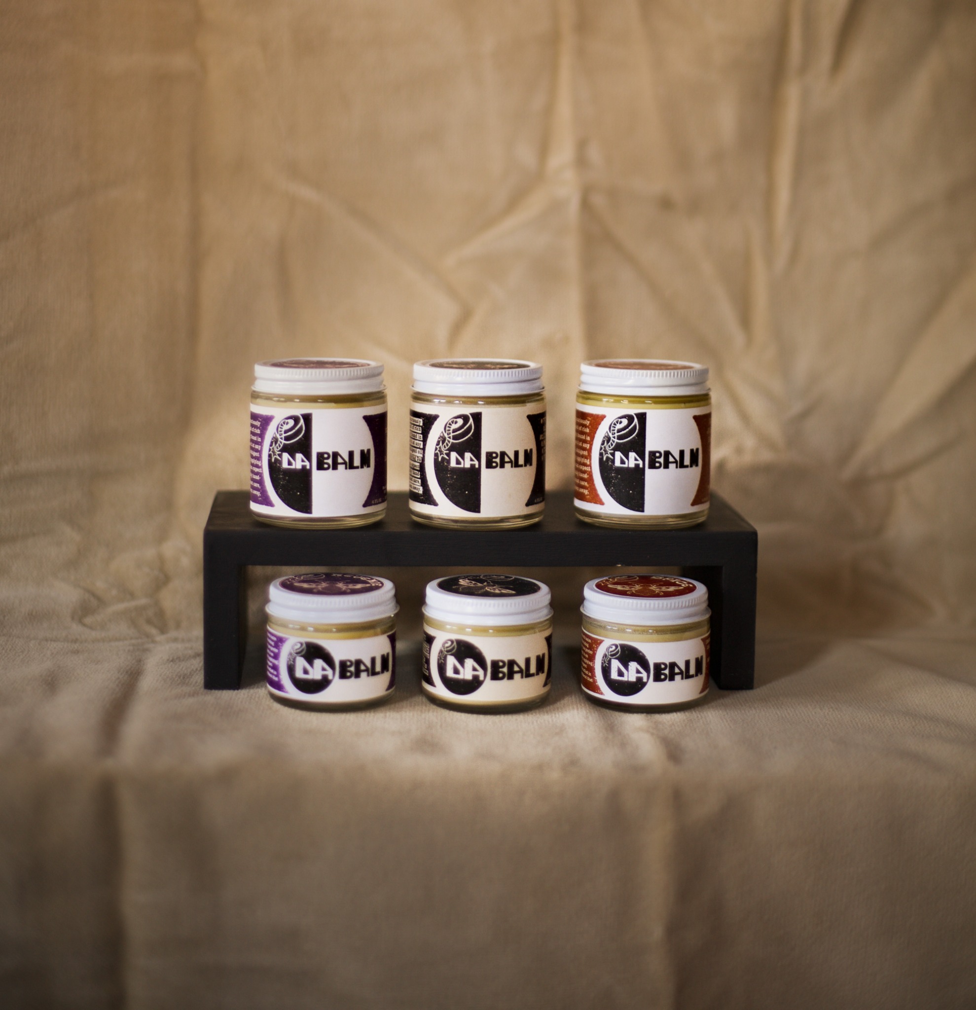 Da Balm jars in multiple sizes and scents on a display stand